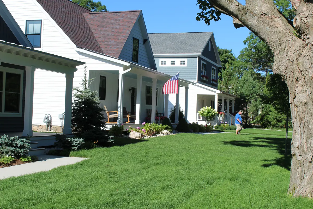 Landscaped front yard with green lawn and white farmhouse
