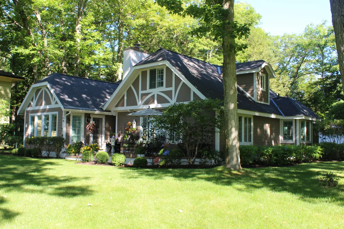 Tudor home with dark roof and white trim in the woods