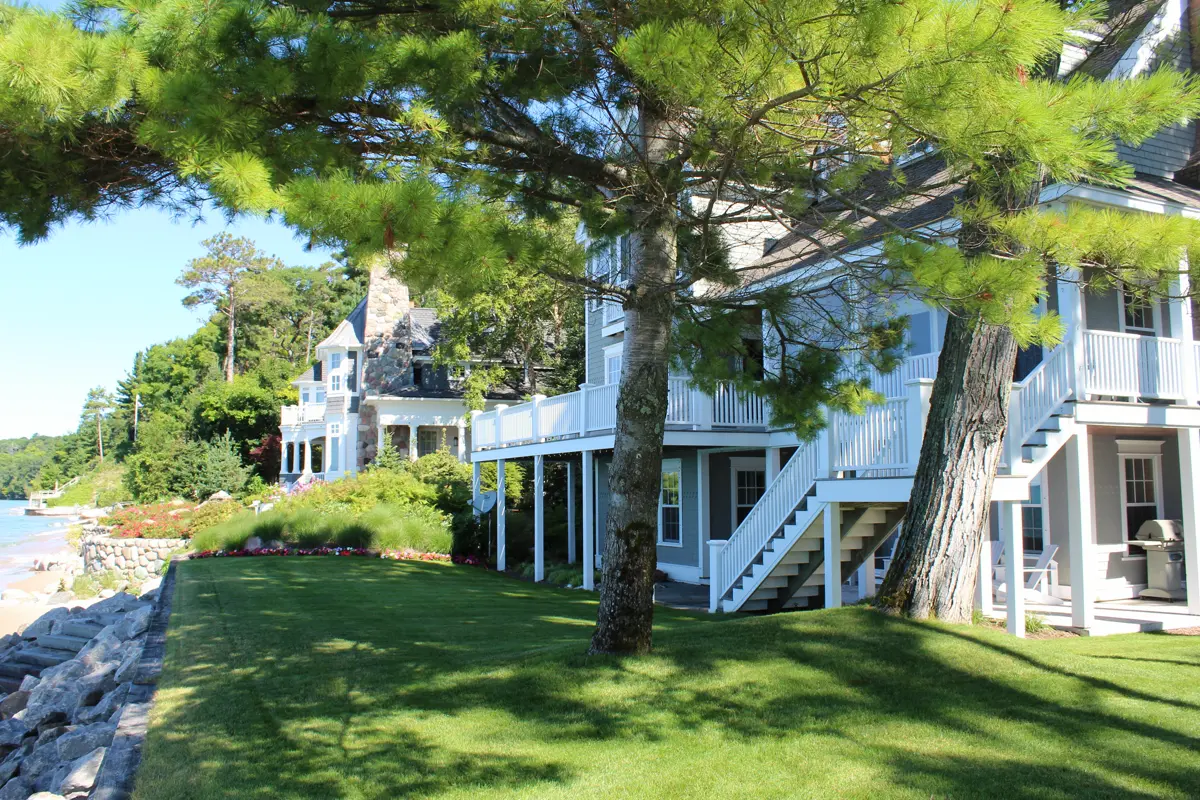 White waterfront homes with porches on grassy lawn