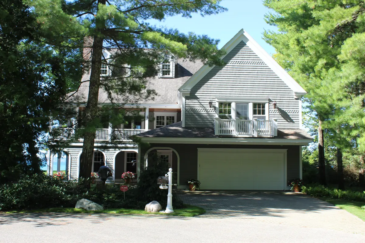Two-story gray house with garage surrounded by trees