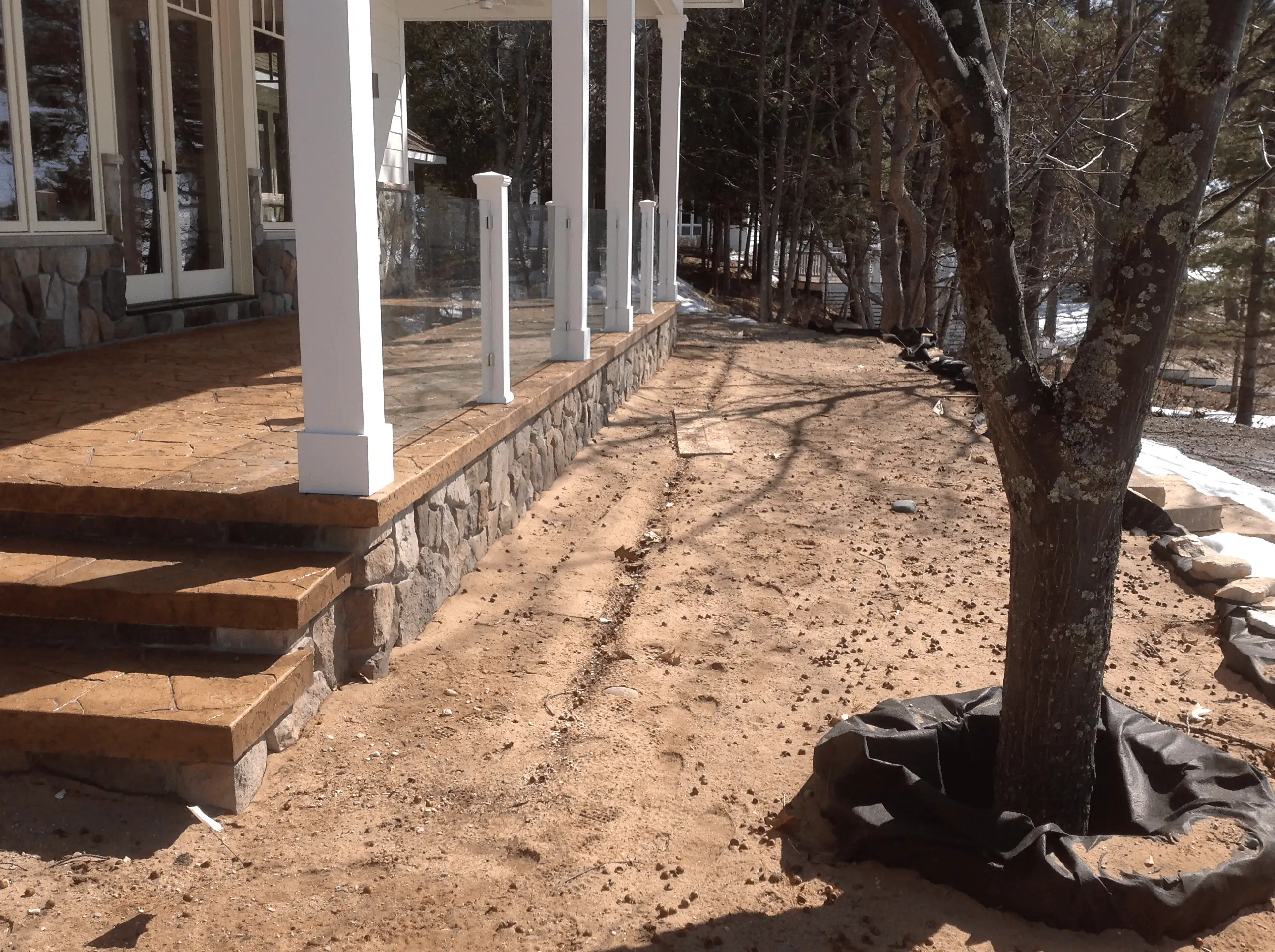 Before: newly built home with bare soil and no landscaping around the porch and patio.